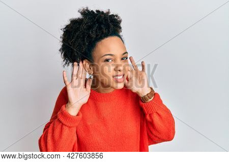 Young african american girl wearing casual clothes trying to hear both hands on ear gesture, curious for gossip. hearing problem, deaf 