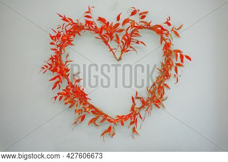 Arranged Heart Symbol Of Ruscus Branches With Red Leaves On A Light Background.