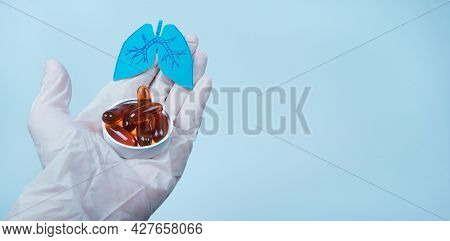 Paper Lungs And White Pills On Doctor's Gloved Hand, Blue Background. Omega-3 Supplements Reduce Ris