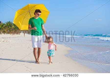 Padre e figlia in spiaggia con ombrellone per nascondere da sole