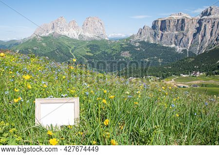 Empty Wooden Picture Frame Mockup In Sunlight. Mountain In Summer With Grass And Flowers In The Fore