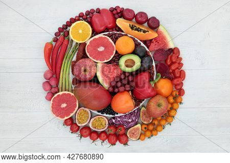 Low cholesterol immune system boosting health food with fruit,  vegetables high in lycopene, anthocyanins, antioxidants, dietary fibre, minerals, vitamins, omega 3. Circular design on rustic wood.