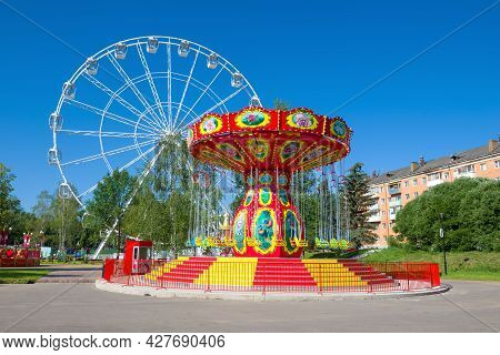 Velikie Luki, Russia - July 04, 2021: Colorful Carousel Against The Background Of The Ferris Wheel I