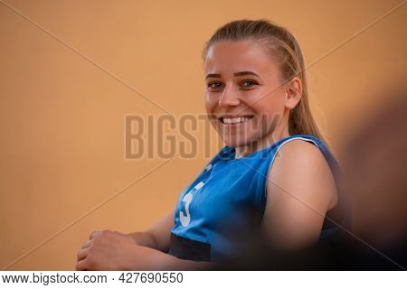 a portrait of a woman with a disability sitting in a wheelchair waiting for a basketball game to begin