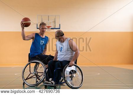 handicapped war veterans in wheelchairs with professional equipment play basketball match in the hall.the concept of sports with disabilities