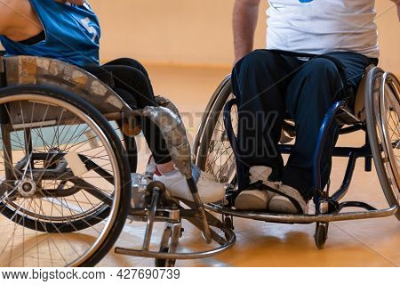 Close up photo of wheelchairs and handicapped war veterans playing basketball on the court