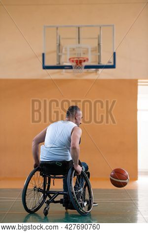 a war  in a wheelchair trains with a ball at a basketball club in training with professional sports equipment for the disabled. the concept of sport for people with disabilities