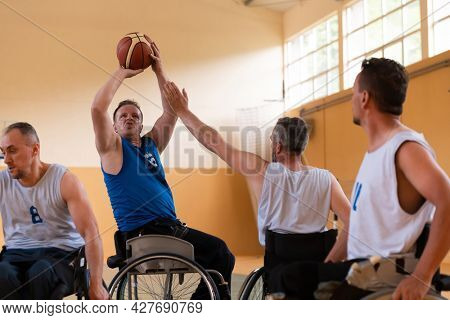 handicapped war veterans in wheelchairs with professional equipment play basketball match in the hall.the concept of sports with disabilities