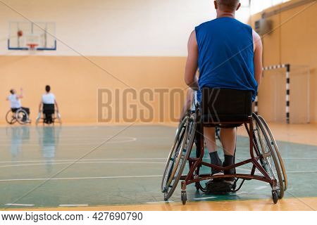 Close up photo of wheelchairs and handicapped war veterans playing basketball on the court