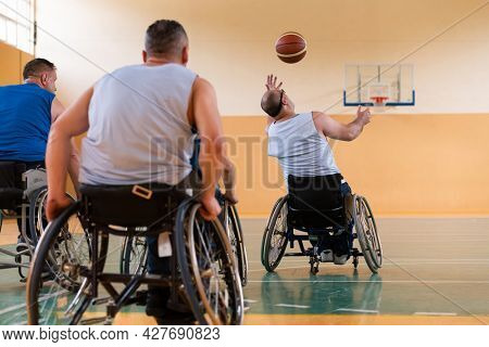 handicapped war veterans in wheelchairs with professional equipment play basketball match in the hall.the concept of sports with disabilities