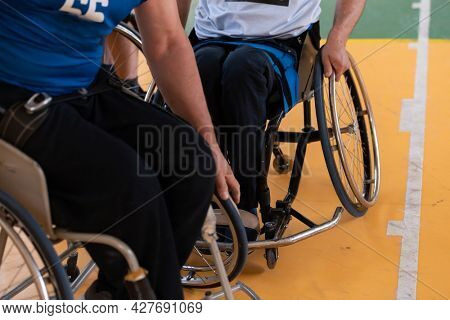 Close up photo of wheelchairs and handicapped war veterans playing basketball on the court