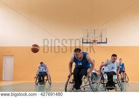 handicapped war veterans in wheelchairs with professional equipment play basketball match in the hall.the concept of sports with disabilities
