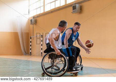handicapped war veterans in wheelchairs with professional equipment play basketball match in the hall.the concept of sports with disabilities