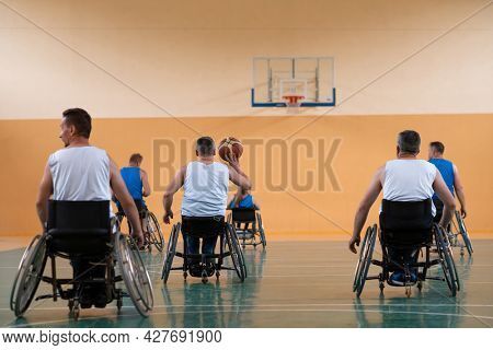 handicapped war veterans in wheelchairs with professional equipment play basketball match in the hall.the concept of sports with disabilities