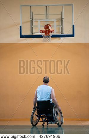 a war  in a wheelchair trains with a ball at a basketball club in training with professional sports equipment for the disabled. the concept of sport for people with disabilities