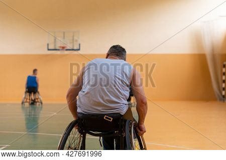 Close up photo of wheelchairs and handicapped war veterans playing basketball on the court
