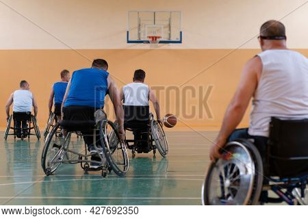 handicapped war veterans in wheelchairs with professional equipment play basketball match in the hall.the concept of sports with disabilities