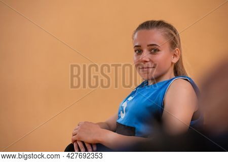 a portrait of a woman with a disability sitting in a wheelchair waiting for a basketball game to begin