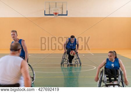 handicapped war veterans in wheelchairs with professional equipment play basketball match in the hall.the concept of sports with disabilities