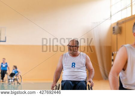 a photo of a war veteran playing basketball with a team in a modern sports arena. The concept of sport for people with disabilities