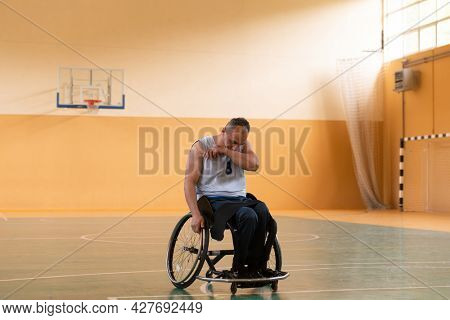 a photo of a war veteran playing basketball with a team in a modern sports arena. The concept of sport for people with disabilities