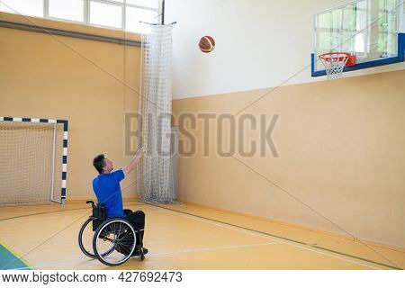 a war  in a wheelchair trains with a ball at a basketball club in training with professional sports equipment for the disabled. the concept of sport for people with disabilities