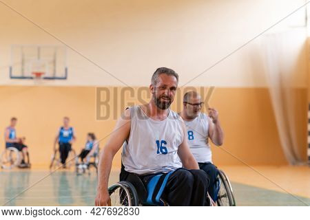 a photo of a war veteran playing basketball with a team in a modern sports arena. The concept of sport for people with disabilities