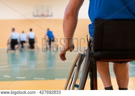 Close up photo of wheelchairs and handicapped war veterans playing basketball on the court