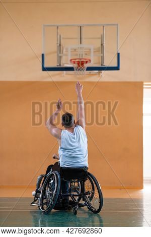 a war  in a wheelchair trains with a ball at a basketball club in training with professional sports equipment for the disabled. the concept of sport for people with disabilities