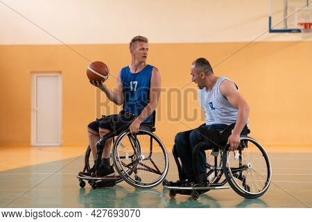 handicapped war veterans in wheelchairs with professional equipment play basketball match in the hall.the concept of sports with disabilities