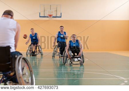 handicapped war veterans in wheelchairs with professional equipment play basketball match in the hall.the concept of sports with disabilities