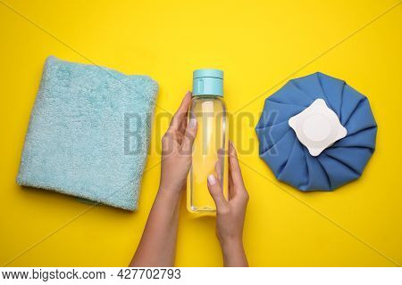 Woman With Bottle Of Water, Cold Compress And Towel On Yellow Background, Top View. Heat Stroke Trea