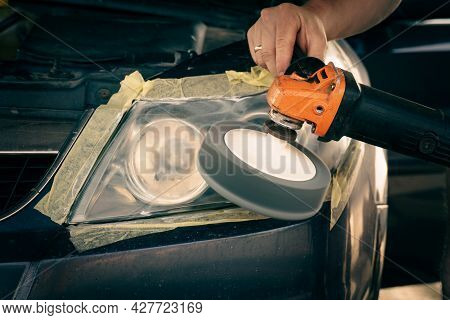 Cleaning Headlights With A Buffer Machine. The Master Polishes The Headlights Of The Car.