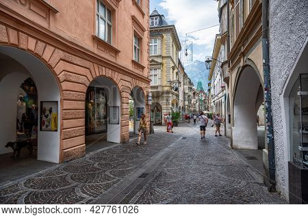 Merano, Italy, June 2021. The Shopping Street Of Merano: Under The Arcades Numerous Shops Attract Cu