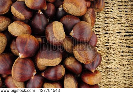 Fresh Ripe Uncooked Spanish Chestnuts In Shells Background