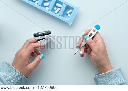 Patient Hands With Pills And Pulse Oximeter, Finger Digital Device To Measure Oxygen Saturation In L