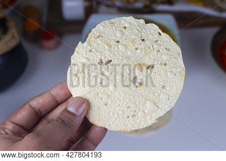 A Person Holding Indian Snack Papd In Hand Isolated On Light Background.