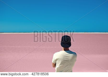 Back View Of Unrecognizable Man, Wearing Gray Tshirt And Baseball Cap, Standing Against Pink Lanke A