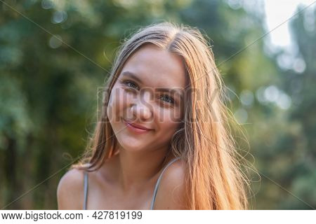 Young Girl 16 Years Old, Charming Brunette With Long Hair, Open Smile, Against The Background Of The