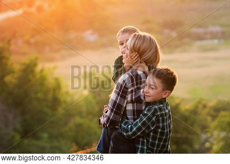 Young Single Mother Having Fun With Her Two Sons Playing Outdoor At Sunset Enjoying Bright Summer Da