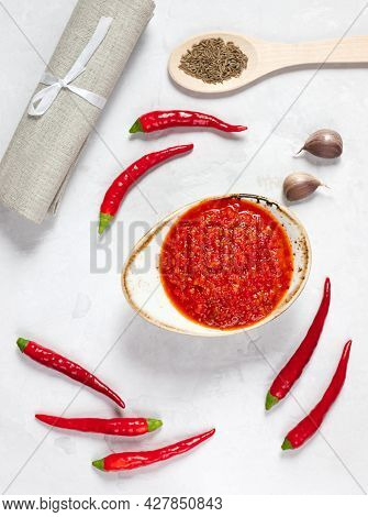 Harissa Paste. Hot Chili Pepper Sauce On A White Background. Adjika In A Bowl With Chili, Garlic And