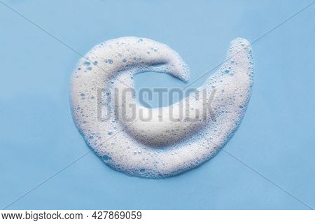 Face Cleansing Mousse Swirl Sample. White Cleanser Foam Bubbles On Blue Background, Copy Space. Soap