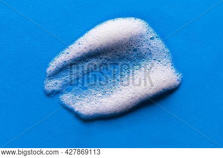 Face Cleansing Mousse Sample. White Cleanser Foam Bubbles On Blue Background. Soap, Shower Gel, Sham