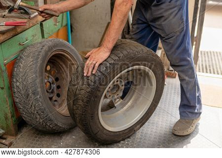 Mechanic Changing Tire In Car Service. Tire Rotation Machine.car Mechanic Mounts Tire On Wheel In A 
