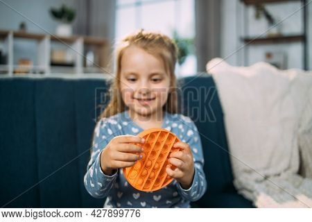 Antistress Toy, Childhood. Happy Smiling Little 4-aged Girl With Colorful Poppit Game, Sitting On So