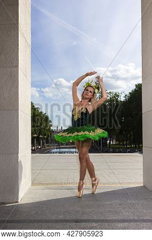 Young Professional Caucasian Ballet Dancer In Green Tutu Dress And Artistic Crown Posing Between Two