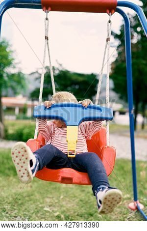 Little Girl Trying To Get Off The Swing By Opening The Jumper