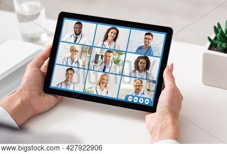 Doctor Lady Making Video Call With Colleagues Using Tablet Indoor