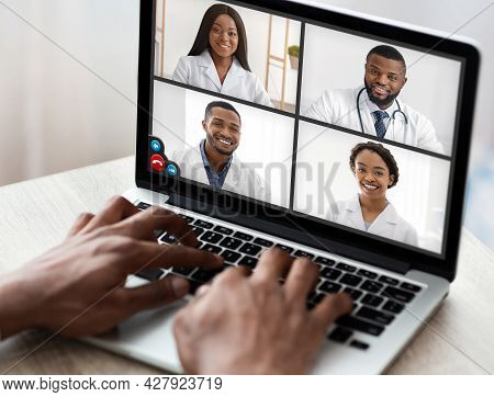 Black Man Using Laptop Video Calling Team Of Doctors Indoors