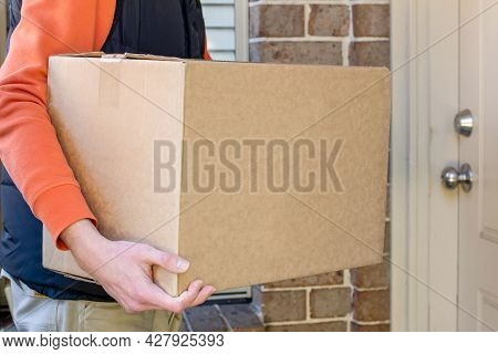 Parcel Box Delivered To A Front Door Of Residential Building By Delivery Courier Man. Online Shoppin